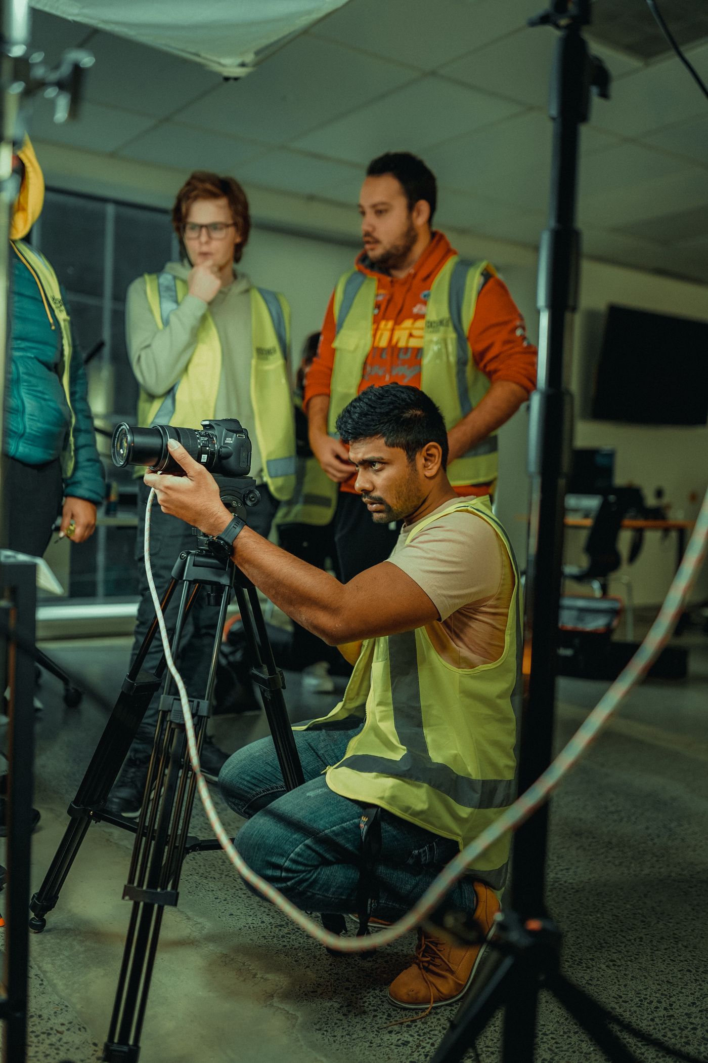 A film crew setting up a camera on a tripod inside a studio
